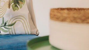 En blå sofa med dekorative puder, et rundt grønt bord og en vægmonteret lampe.