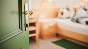 Ein Zimmer mit einer grünen Tür, einem Bett, einem Nachttisch und einer Lampe.