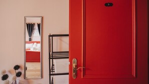 A red door with a number plate, a mirror, and a black metal rack with white baskets. - Room 'Garni Unterweggütl Love' with Mountain View, Shared Pool and Wi-Fi (Naturno)