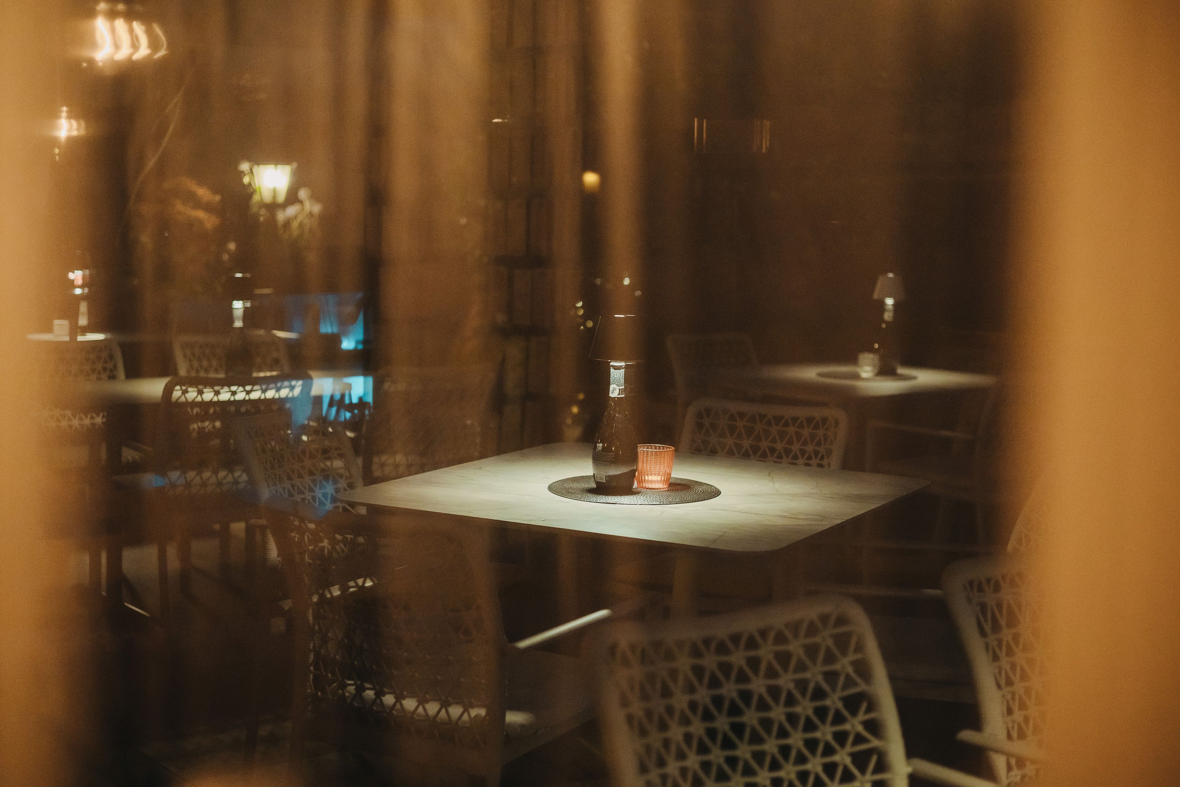 Ein Restaurantinneres in gedämpftem Licht mit Tischen und Stühlen.