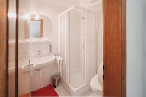 Een badkamer met douche, wastafel en toilet.