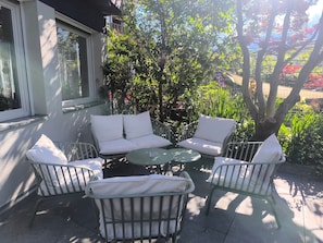 An outdoor seating area with a table and chairs, surrounded by greenery and a building. - Room 'Tiroler' with Mountain View, Shared Pool and Wi-Fi (Naturno)