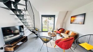 A modern living room with a spiral staircase, a large flat-screen TV, and a sofa set. - Avocet - Laïta (Guidel)