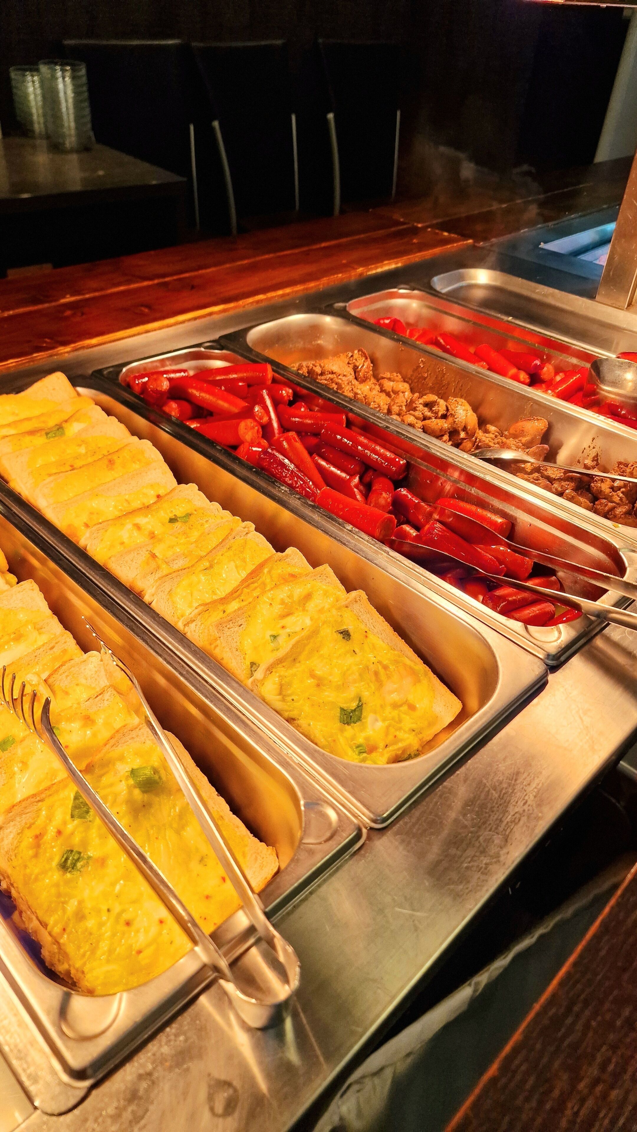 A buffet with various food options including omelets, red peppers, and fried chicken.