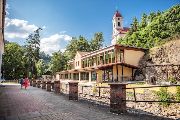Un edificio con una torre, un corredor cubierto y un promontorio rocoso.