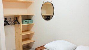 Ein Schlafzimmer mit Bett, weißen Kissen, einem Holzschrank und einem Wandspiegel.