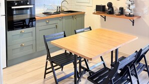 Eine Küche mit einem Holztisch, Stühlen, einer Mikrowelle, einem Backofen und einem Spülbecken.