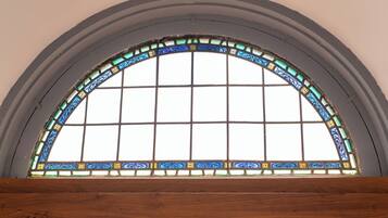 A large arched window with a grid pattern and decorative stained glass.