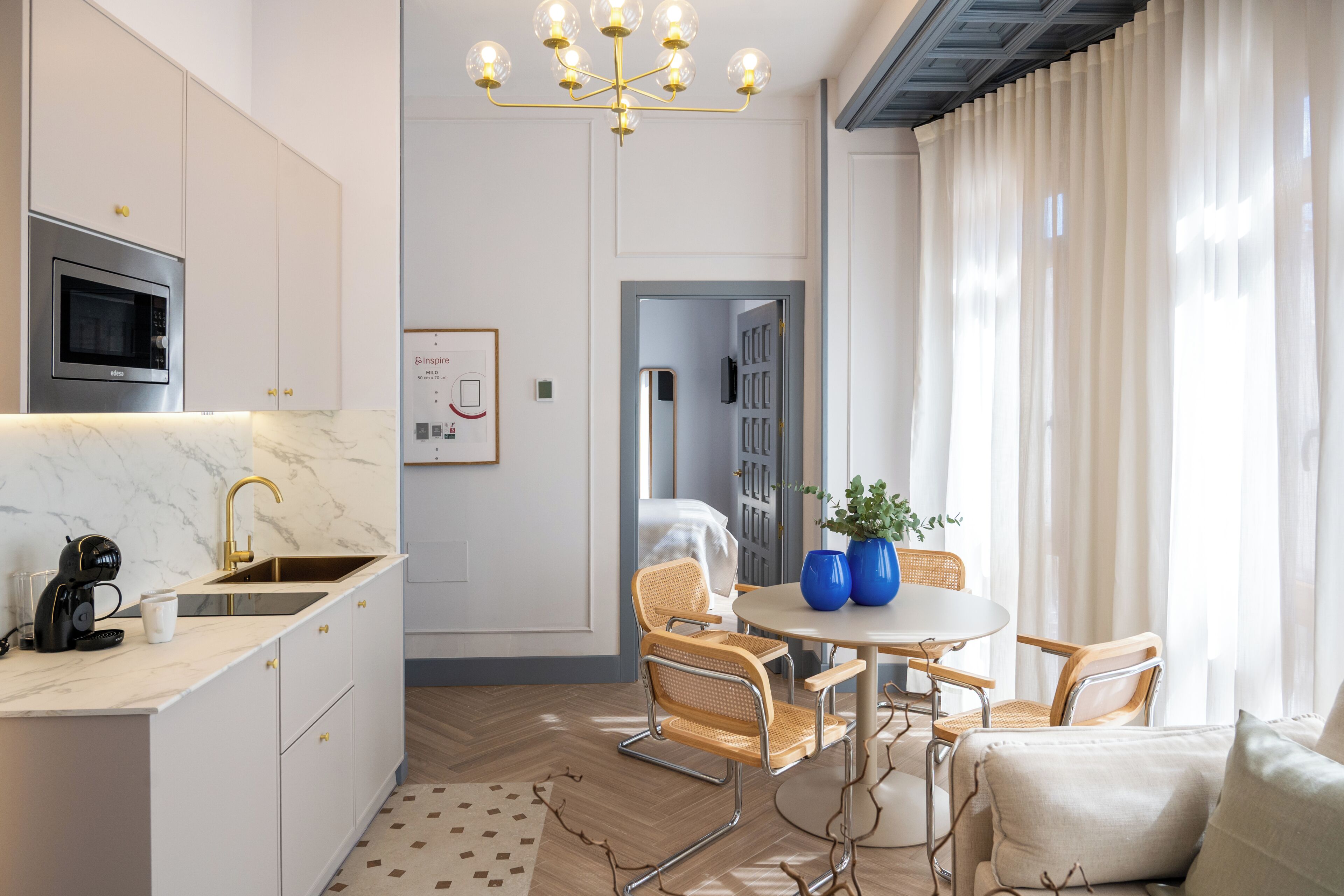 Una cocina moderna con microondas integrado, un fregadero y un comedor con una mesa redonda y sillas.