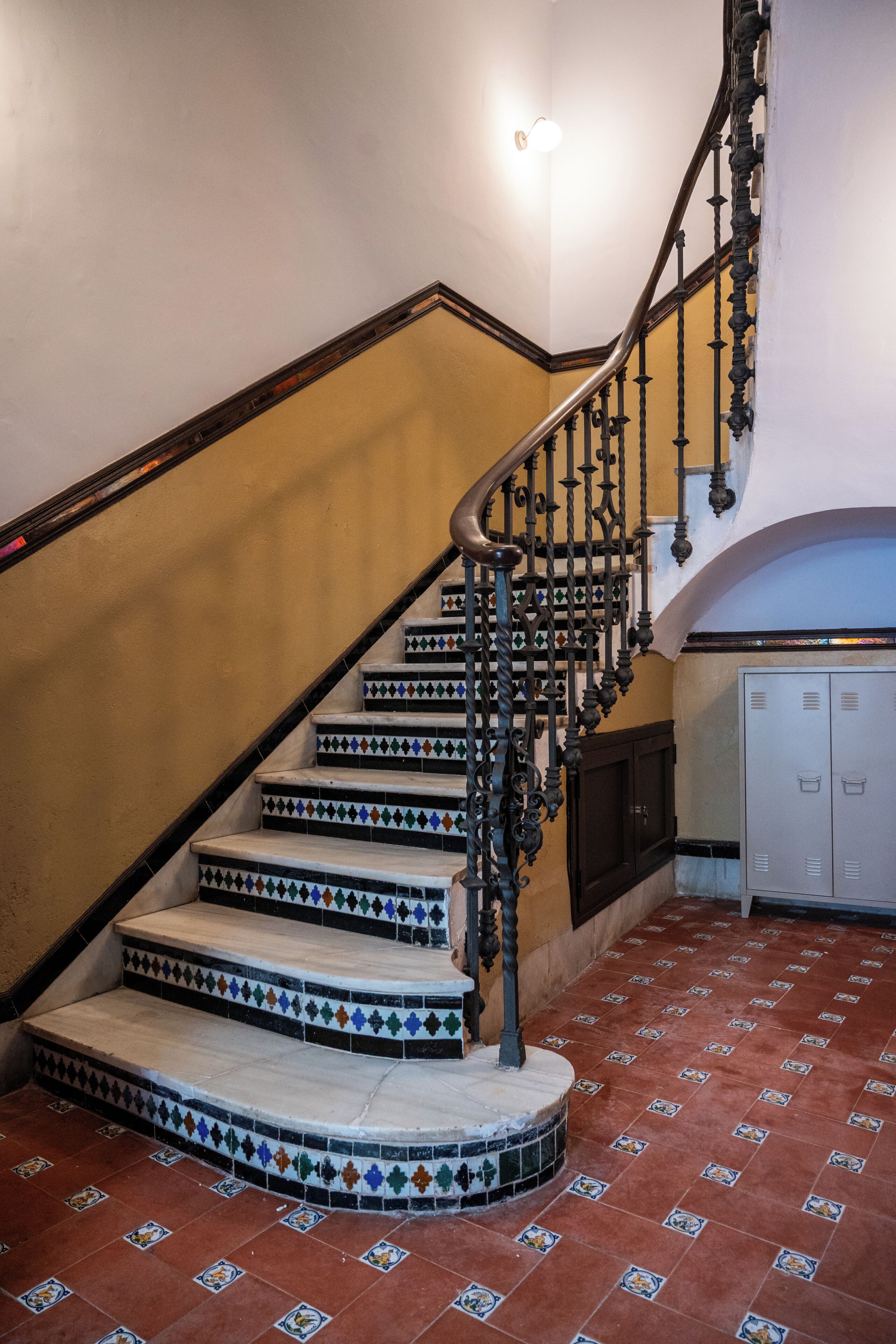 Una escalera con barandillas de metal ornamentadas y baldosas con diseños.