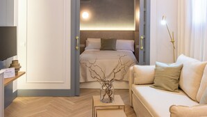 A modern hotel room with a bed, a sofa, a desk, and a television.