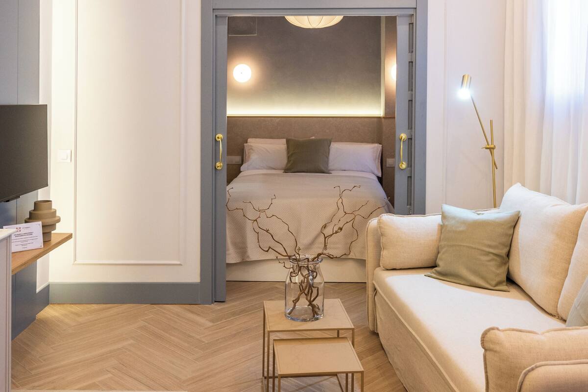 Ein modernes Hotelzimmer mit Bett, Sofa, Schreibtisch und Fernseher.
