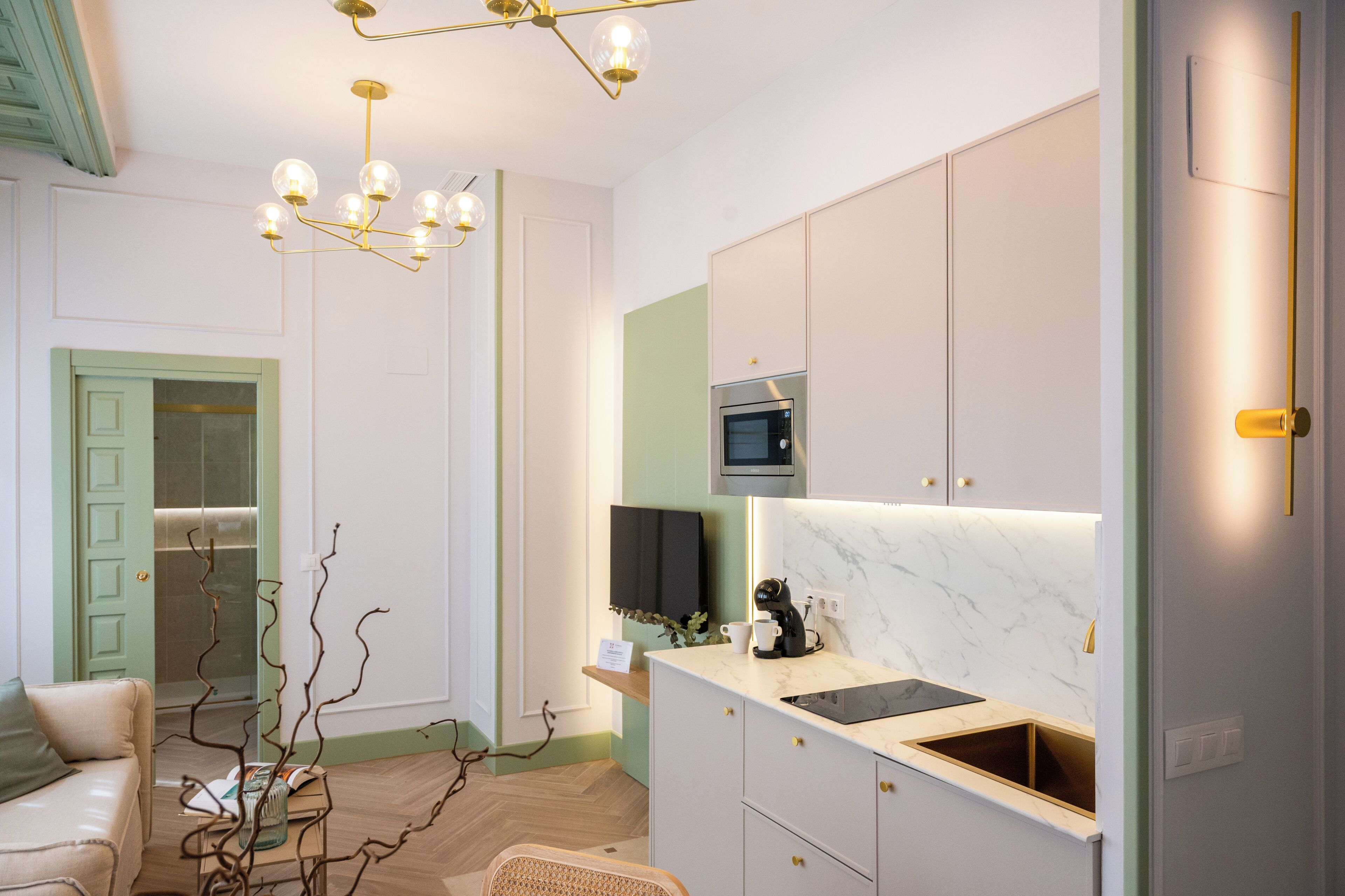 A modern kitchen with a built-in oven, a coffee machine, and a TV above the counter.