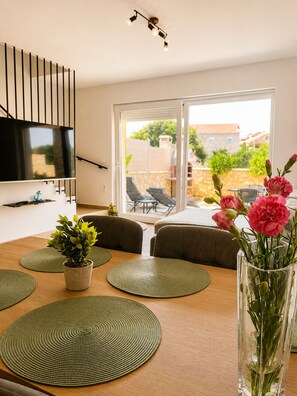 A dining area with a wooden table, green placemats, and a potted plant. - Apartment Mariner 1 with heated pool (Zaton)