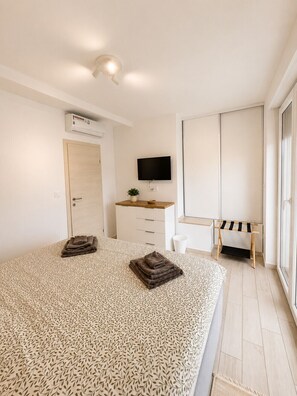 Ein Schlafzimmer mit einem Bett, einem Fernseher, einem Schreibtisch und einem Kleiderschrank.