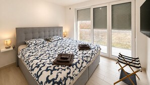 Makuuhuoneessa on suuri sänky, yöpöytä lampulla, ikkuna, jossa on sälekaihtimet, ja kokoontaitettava tuoli.