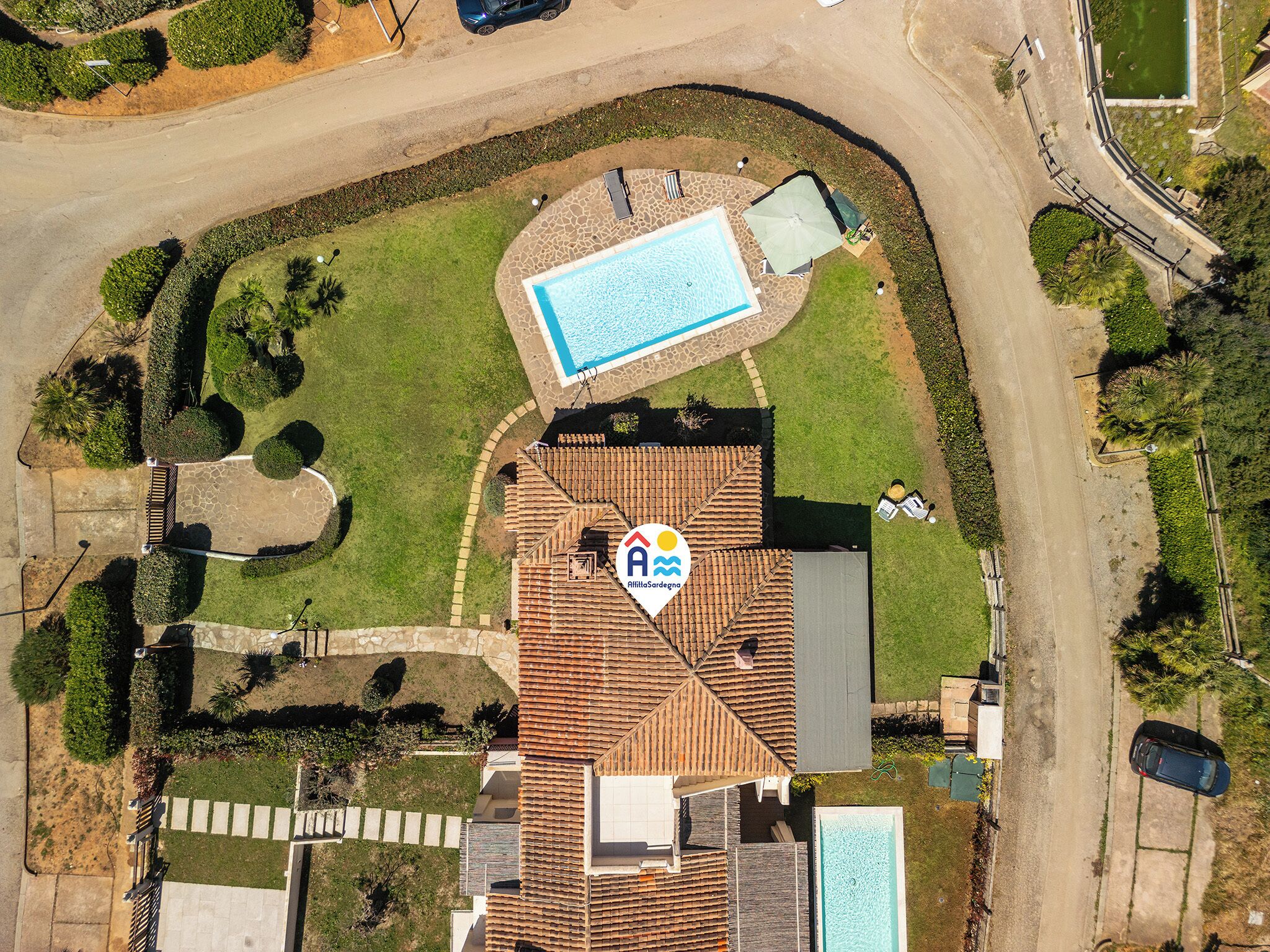 An aerial view of a residential property with a swimming pool, a patio area, and a well-maintained garden.
