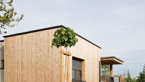 A modern building with a wooden exterior, a small window, and a well-maintained lawn. - Oaza Luxury Resort (Moravske Toplice)