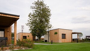 A modern building with a wooden facade, a large tree in the center, and a well-maintained lawn. - Oaza Luxury Resort (Moravske Toplice)