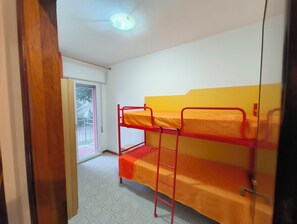 A room with bunk beds, a window with a view, and a door. - Welcoming apartment for five guests in Rosolina (Rosolina Mare)