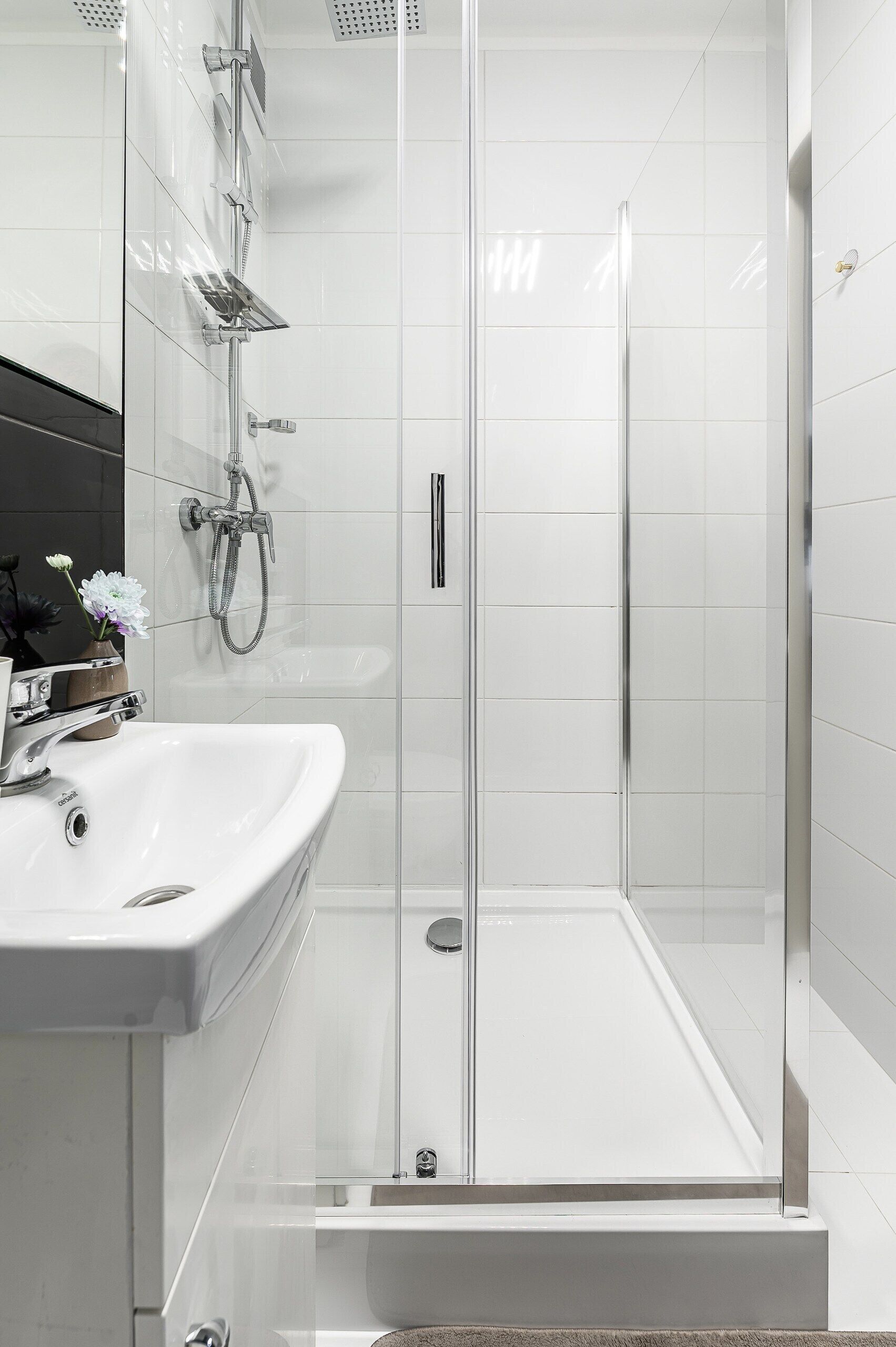A modern bathroom with a glass-enclosed shower, a white sink, and a mirror.