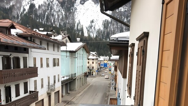 Ein Balkon mit Blick auf ein Gebirge, einem Holzzaun und Häusern mit Balkonen.