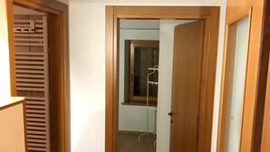 Ein Flur mit Holztüren, einem weißen Heizkörper und einem gefliesten Boden.