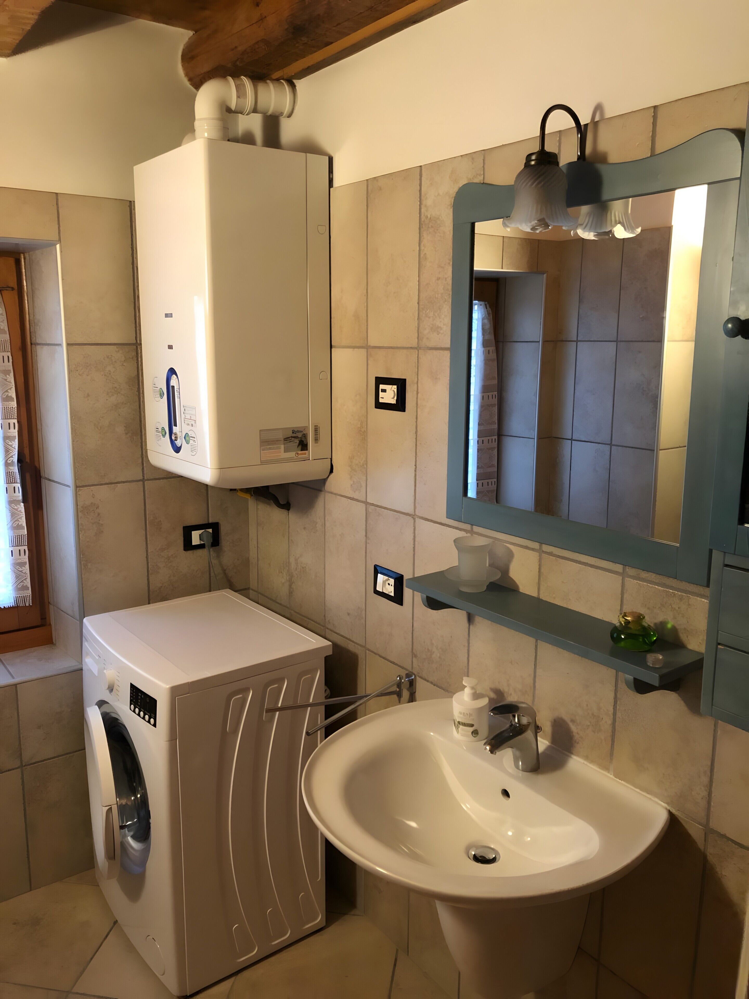 Un baño con lavadora, lavamanos, espejo y toallero.