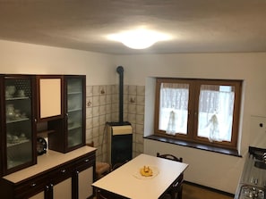 Una cocina con estufa, una mesa de comedor y un ventanal con cortinas.