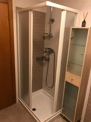 A corner shower with a glass enclosure, a showerhead, a handheld shower, and a glass cabinet with drawers. - Apartment 'Nina' with Shared Terrace and Wi-Fi (Santo Stefano di Cadore)