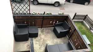 A rooftop patio with four dark wicker chairs, a concrete floor, and a wooden fence. - Apartment 'Nina' with Shared Terrace and Wi-Fi (Santo Stefano di Cadore)
