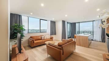 A modern living room with a sofa, coffee table, and a TV on a wooden stand.