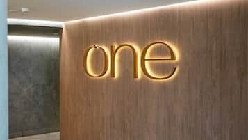 A reception area with a wooden wall and a 'one' sign illuminated in gold.