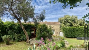 A stone house with a tiled roof, surrounded by a garden with various plants and a tree. - House 6 persons between vineyards and garrigues (Pouzilhac)