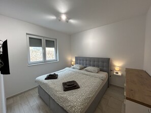 Un dormitorio con una cama, dos lámparas de noche, un ventanal y un ventilador de techo.