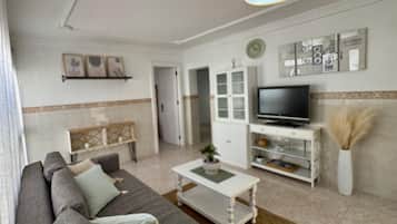 A living room with a sofa, coffee table, TV, and decorative items.