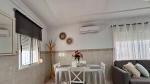 Un comedor con una mesa preparada para cuatro personas, un sofá gris y un árbol decorativo.