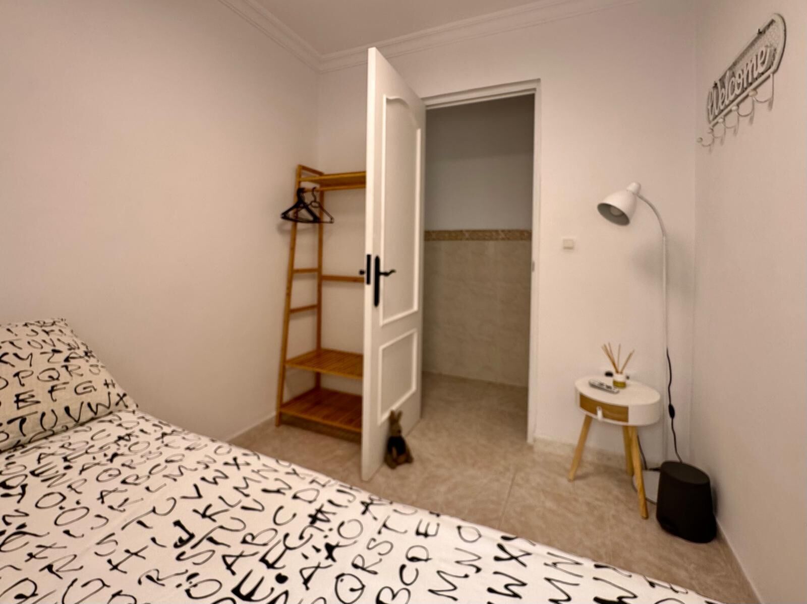 Une chambre à coucher comprenant un lit, une armoire, une petite table avec une lampe et un élément de décoration murale.