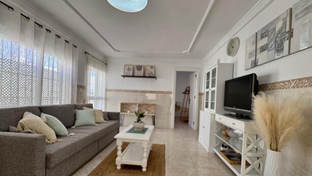 Una sala moderna con un sofá, una mesa de centro, televisor y objetos decorativos.