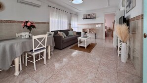Una sala de estar con comedor, un sofá, una mesa de centro y un televisor.