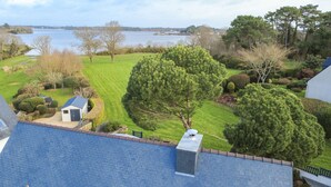 Une propriété résidentielle dotée d’une pelouse, d’un petit abri de jardin et offrant une vue sur un lac.
