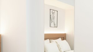 Una habitación de hotel moderna con cama, cabecera y una obra de arte colgada en la pared.