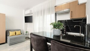 Una cocina moderna con encimera negra, armarios de madera y un sofá gris con cojines amarillos.