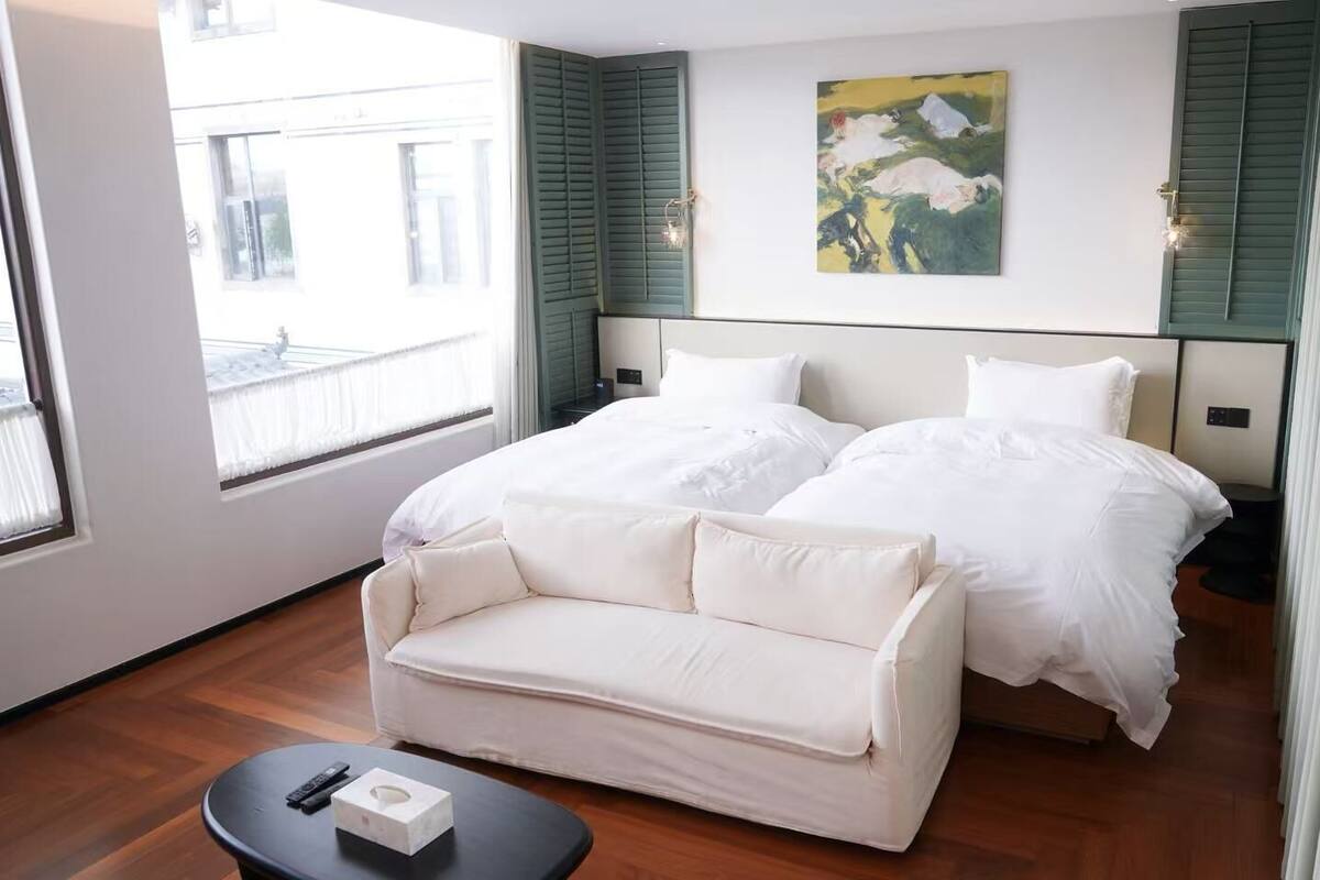 Hotellihuoneessa on sänky, sohva, pieni pöytä ja seinällä taulu.