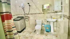 Une salle de bain comprenant des toilettes, un lavabo, une douche et un carrelage décoratif.