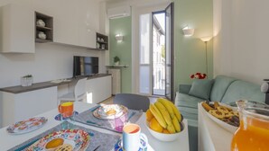 Eine moderne Küche mit Essbereich, einer Couch und einem Tisch, gedeckt mit Speisen und Getränken.