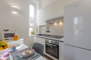 Eine moderne Küche mit weißen Schränken, einer Spüle aus Edelstahl, einem eingebauten Ofen und einem Samsung-Kühlschrank.
