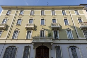Un edificio de varios pisos con balcones ornamentados, ventanas amplias y una entrada central con una puerta decorativa.
