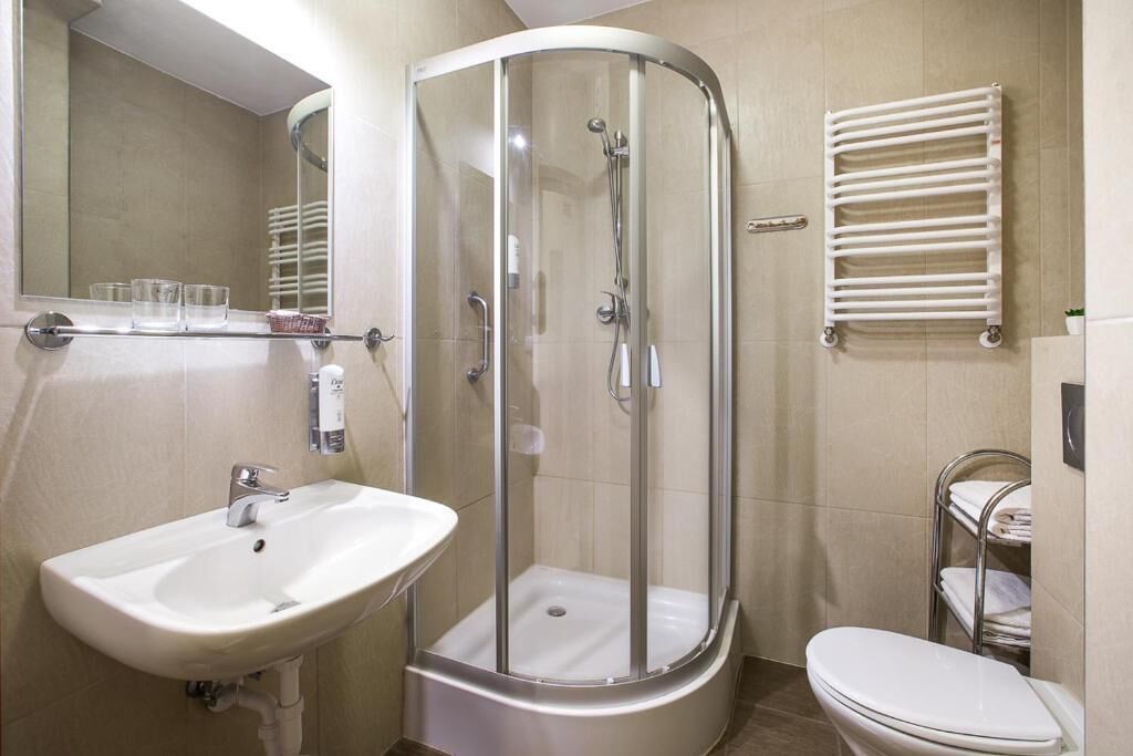 Une salle de bain avec une douche à parois de verre, un lavabo, des toilettes et un porte-serviettes.
