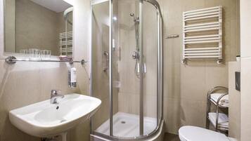 Une salle de bain avec une douche à parois de verre, un lavabo, des toilettes et un porte-serviettes.